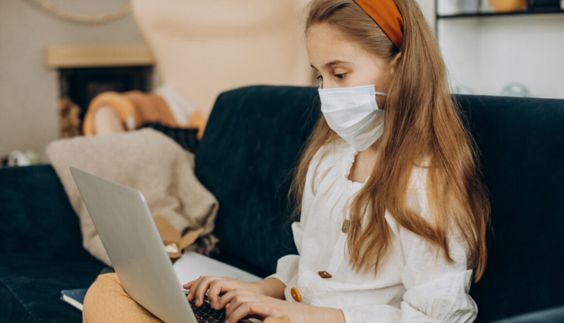 School girl studying at home wearing mask, distant learning